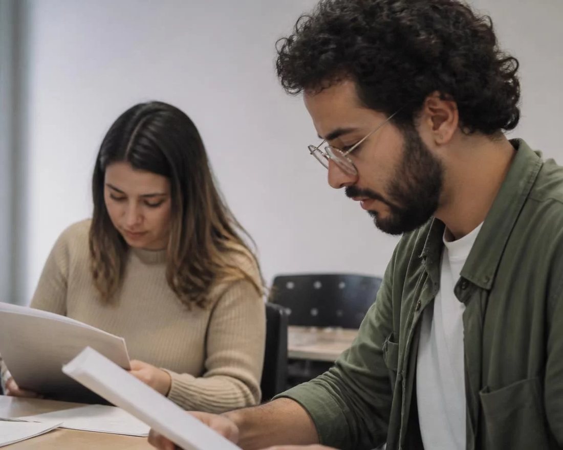 Dupla discute em pé entre as estantes de uma biblioteca, cada um sustentando o seu ponto
